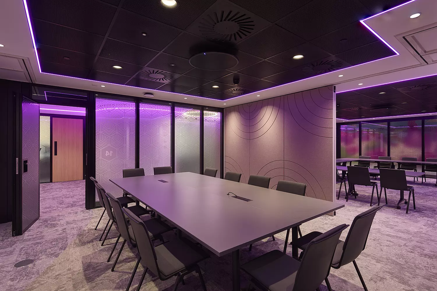 large wooden table with chairs surrounding it and purple lighting