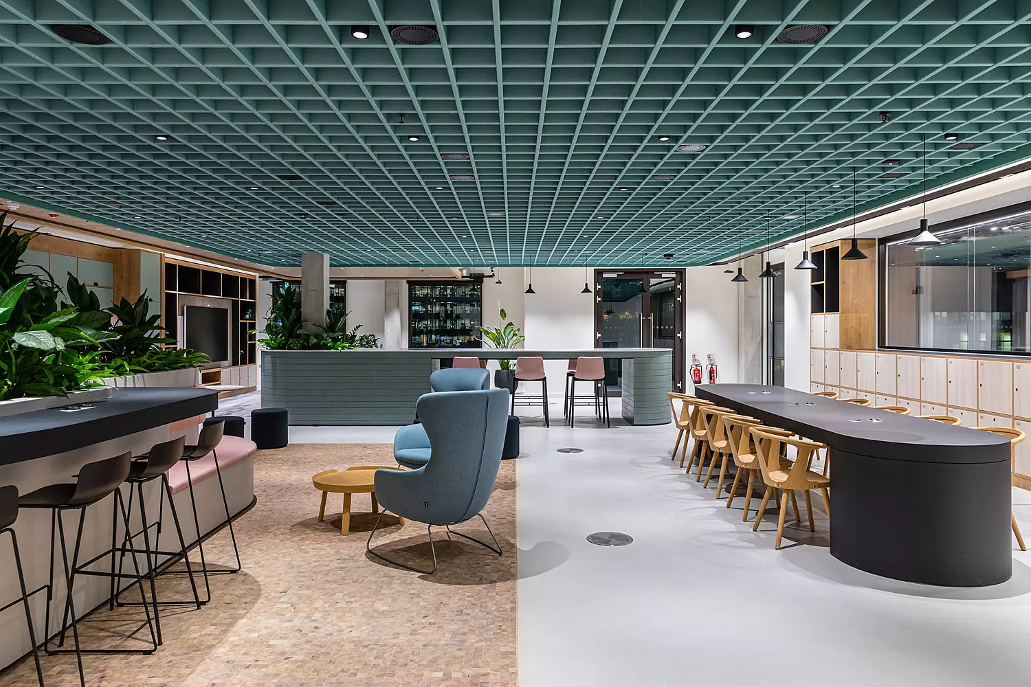 Black bar stools, blue comfy chairs and wooden office chairs in a large open plan space underneath a blue acoustic ceiling feature