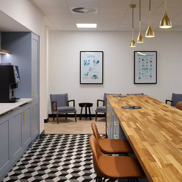 A blue kitchen with island unit and high chair seating