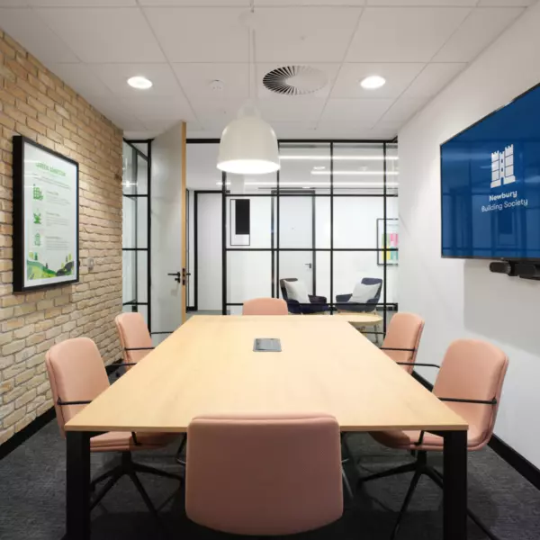 A small pastel meeting room with exposed brickwork and TV