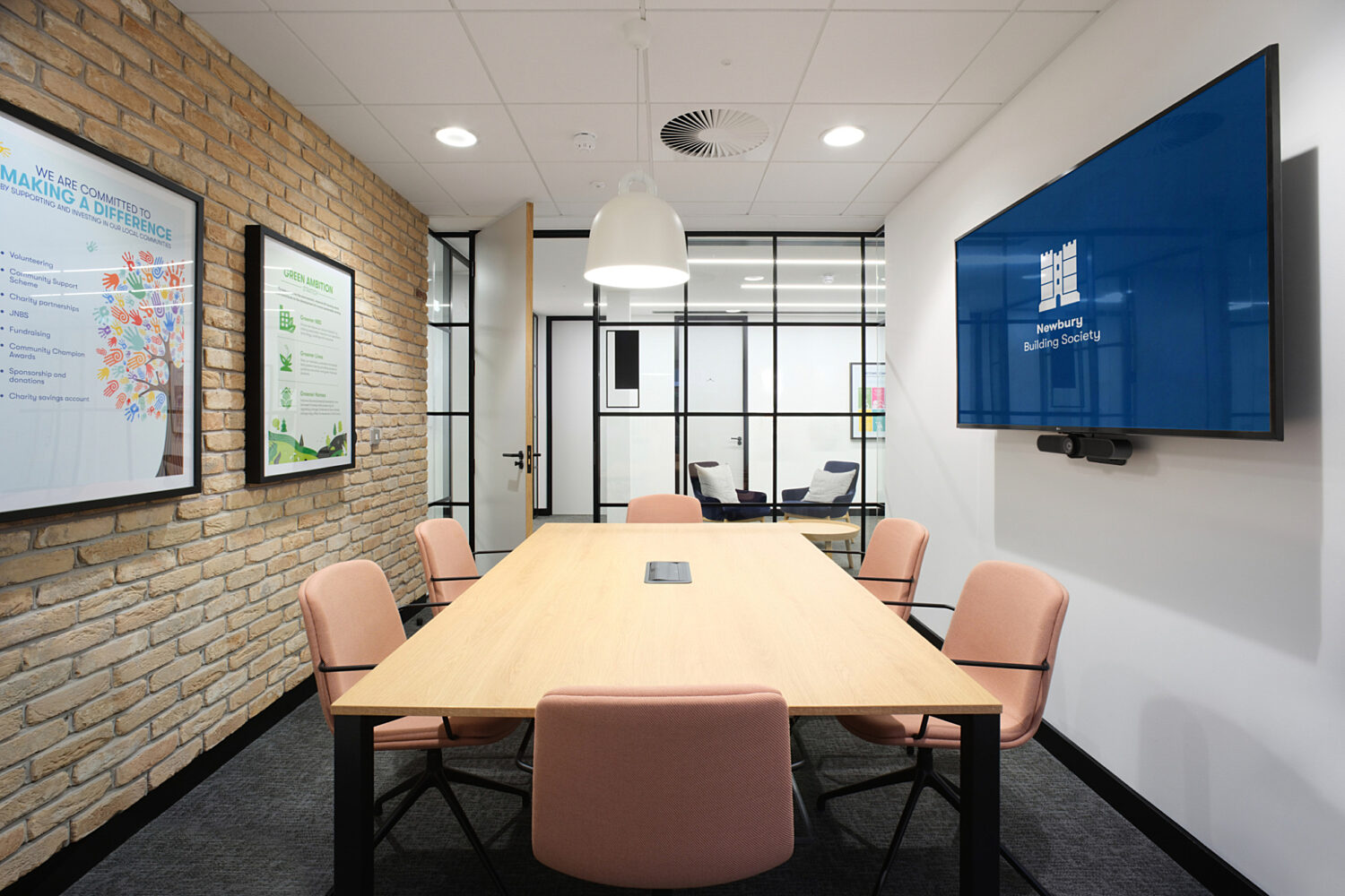 A small pastel meeting room with exposed brickwork and TV