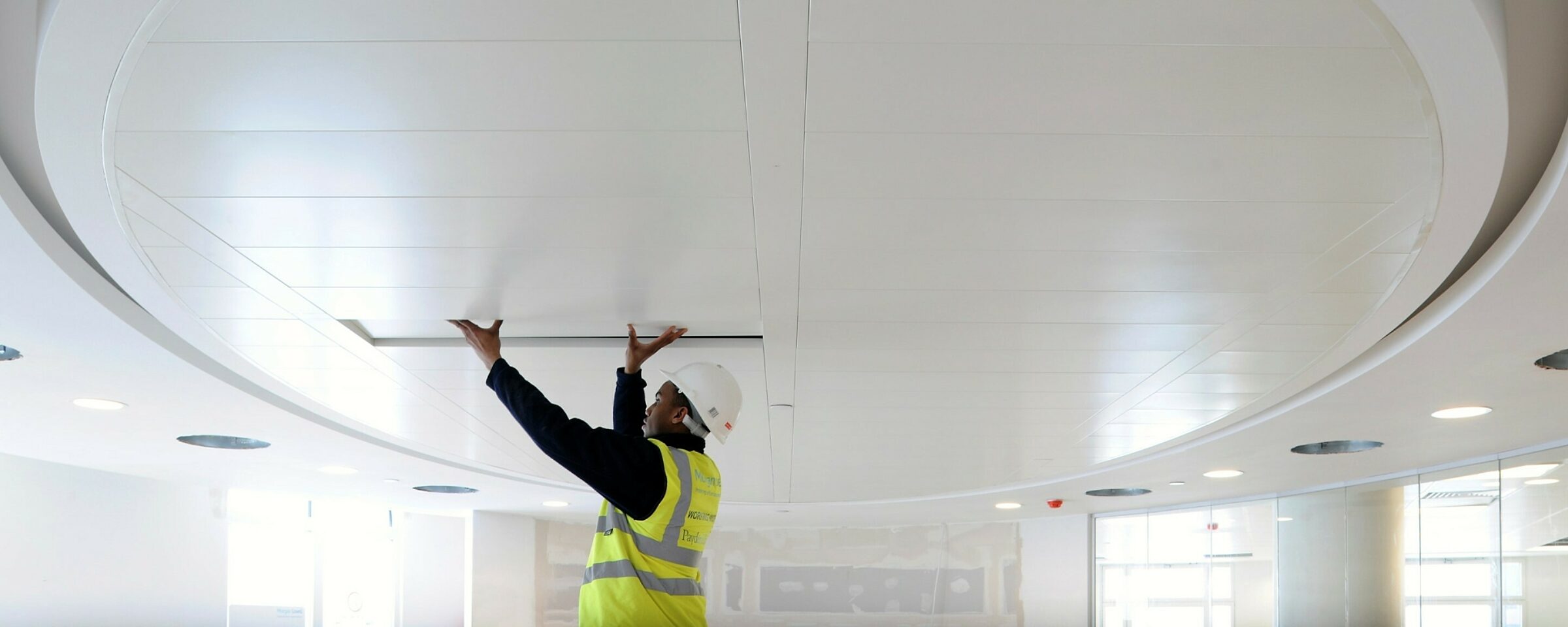 A man in health and safety gear working on the ceiling onsite.