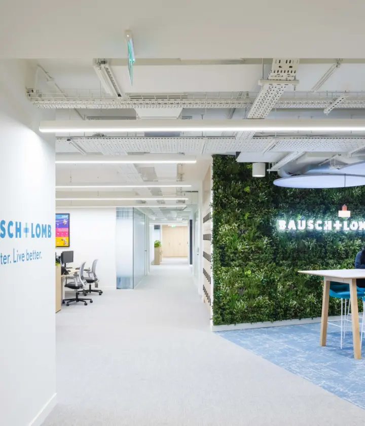 Modern office fit out featuring biophilic office design with a living green wall, open plan workspace, branded reception area and contemporary breakout seating.