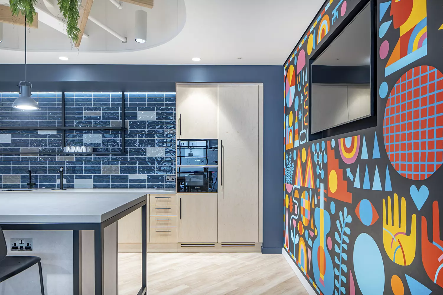 Office kitchen area with brightly coloured patterned feature walls.