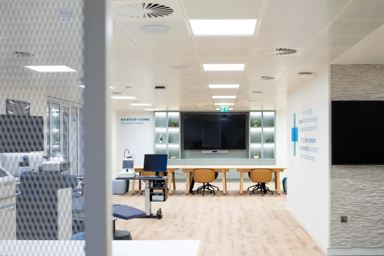 Modern office fit out featuring a collaborative meeting and presentation space with large screen, open plan workspace, glass partitioned rooms, timber flooring and contemporary office design