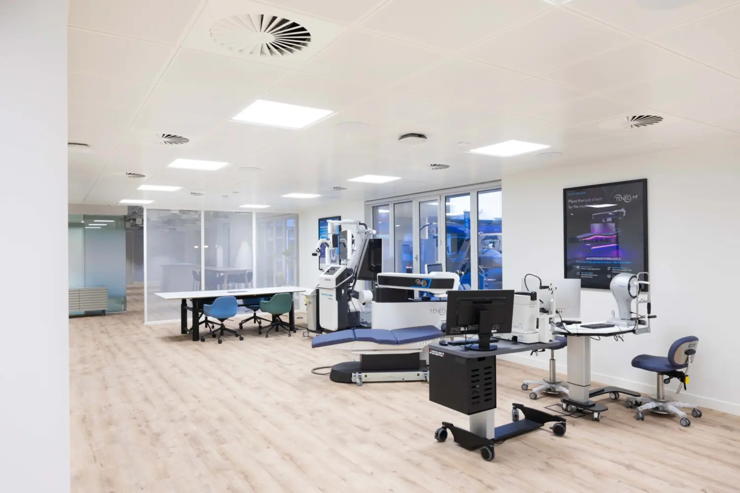 Modern office fit out featuring an open plan training and technical workspace with adjustable desks, integrated technology benches, glass partitioned rooms, timber flooring and a bright contemporary office design