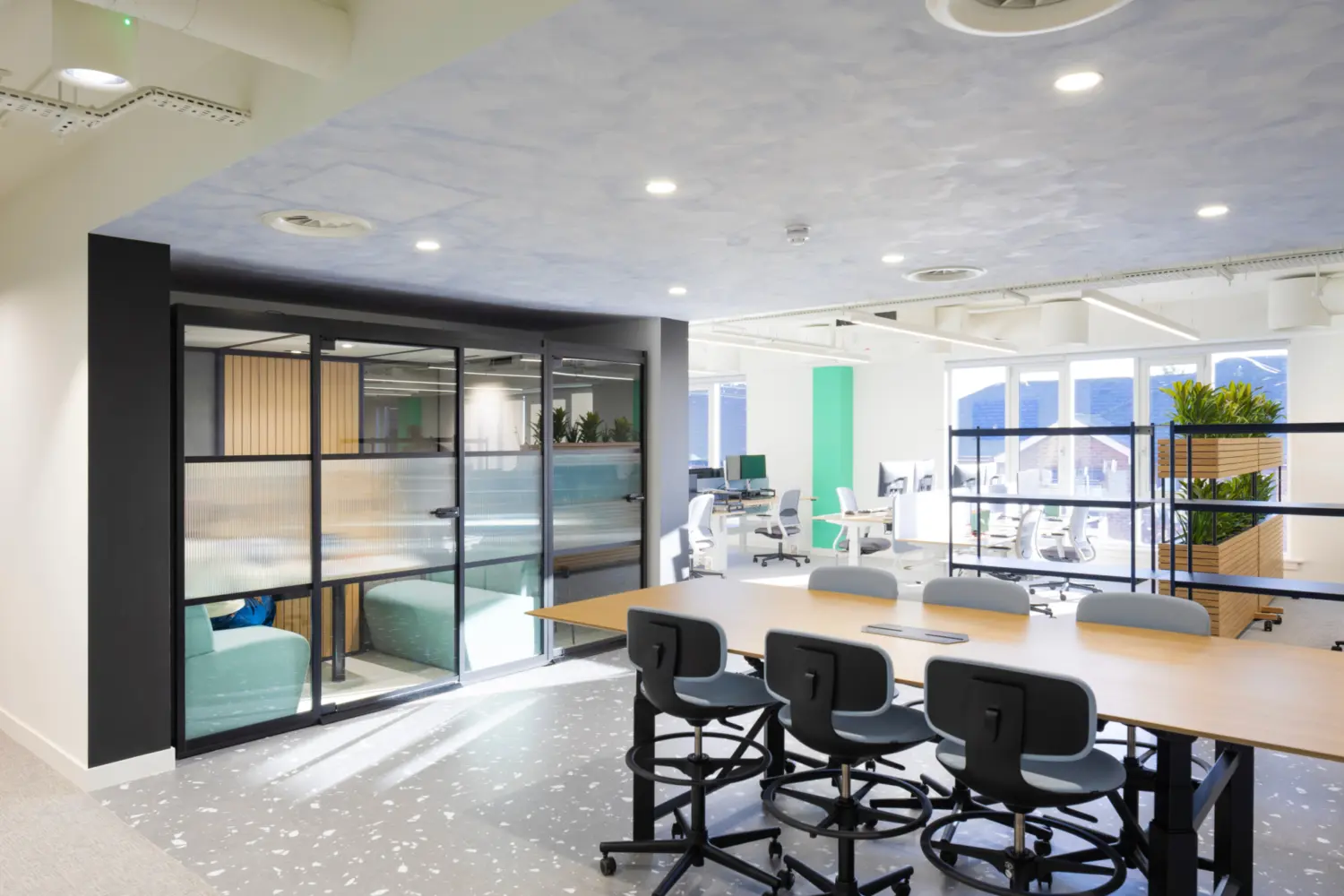 Modern office fit out featuring a collaborative meeting and training space with glass partitioned meeting rooms, open plan office layout, ergonomic task seating and contemporary workplace design.